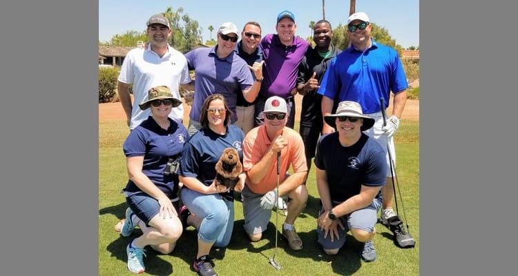 A group of people posing for a photo at the Fighter Country Partnership Golf Classic 2018 on a golf course.