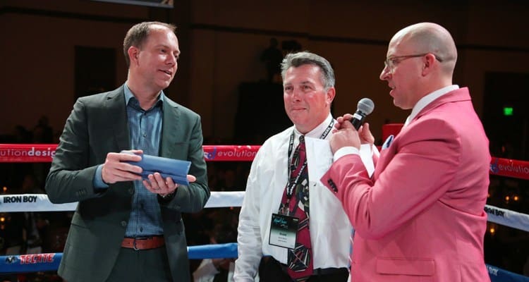 Three men at NAIOP Night at the Fights 2018 in a boxing ring talking to each other.