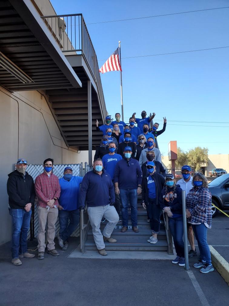 Willmeng volunteers wearing blue face masks pose in front of a building.