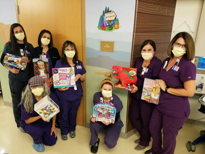 A group of nurses posing with toys in a hospital room.