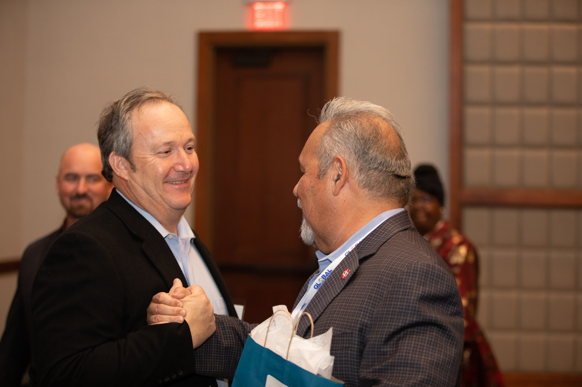 Two members of the ABA Board of Directors shaking hands at an event.