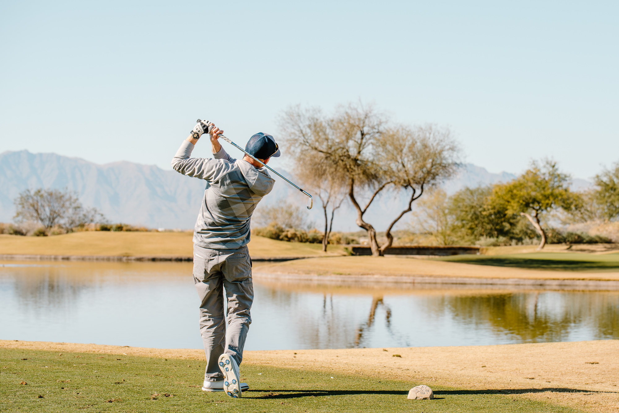 A man enjoying the Spring on the Green, swinging his golf club in front of a pond.