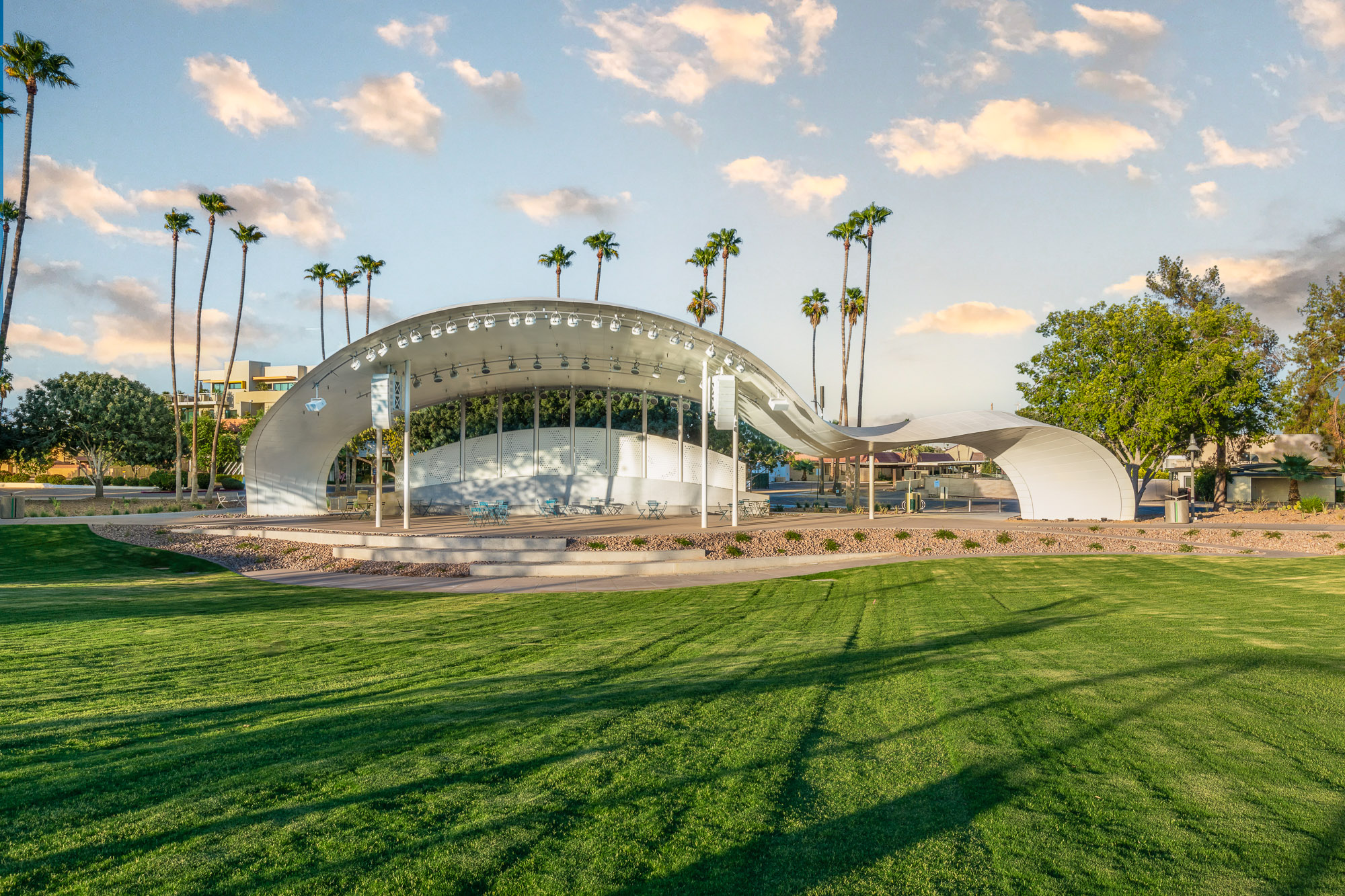 A large white structure situated in the heart of an expansive grassy field, serving as a focal point for recreation development in urban parks.