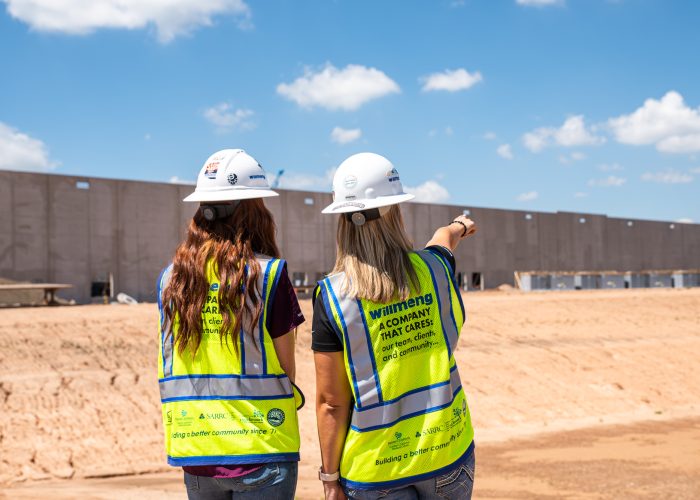 Two women standing in front of a Willmeng Construction site.